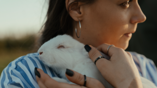 Female holding white rabbit to chest