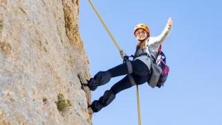 Woman Abseiling whilst giving a thumbs up to the camera